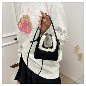 Detail of black suede mini handbag with contrasting white faux fur handle and leather strap