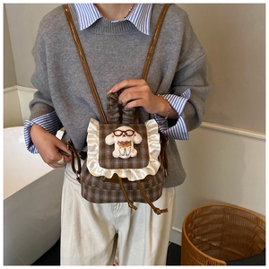 Detail of mini plaid backpack with white ruffle trim and a plush puppy doll accent