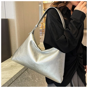 Close-up of metallic silver hobo bag with embossed texture worn by a model