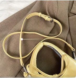 Detail of adjustable shoulder strap with silver buckle on yellow leather shoulder bag