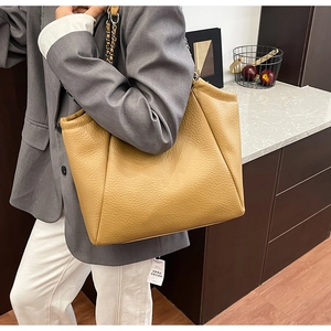 Close-up of bright yellow litchi grain leather tote bag with metal chain strap detail