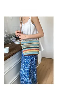 Modella con borsa a secchiello intrecciata arcobaleno e finiture in pelle in un caffè