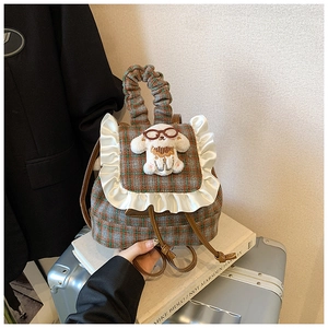 Detail of plaid kids backpack with lace trim and plush puppy on a silver suitcase