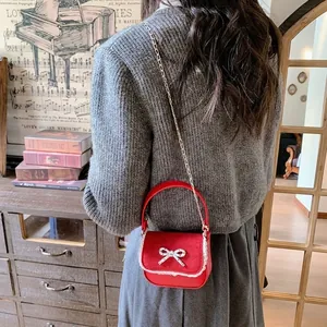 Mini sac bandoulière rouge avec nœud blanc et dentelle présenté sur un mannequin