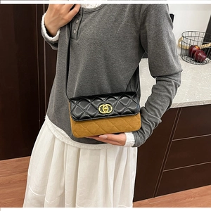 Detail of contrast color crossbody bag with gold double C buckle and quilted leather texture