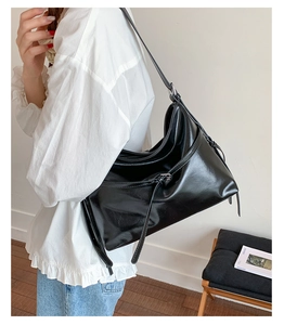 Detail of glossy black PU leather tote bag with stylish thin straps and side fringe