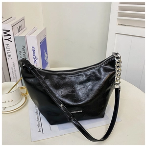 Close-up of black glossy leather hobo bag with silver chain and metal logo detail