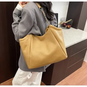 Detail of mustard yellow lychee texture leather hobo bag with gold chain shoulder strap
