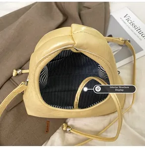 Detail view of yellow quilted dumpling bag showing striped lining and inner pocket