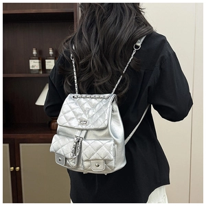 Sac à dos argenté matelassé avec chaînes présenté dans un décor intérieur élégant