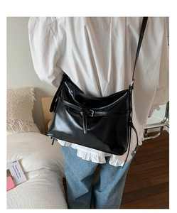 Rear view of a model wearing a black glossy PU leather hobo bag for commuting look