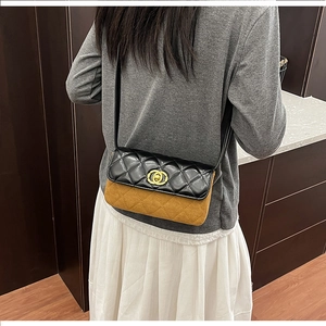 Detail of elegant two-tone crossbody bag with quilted black flap and brown suede body