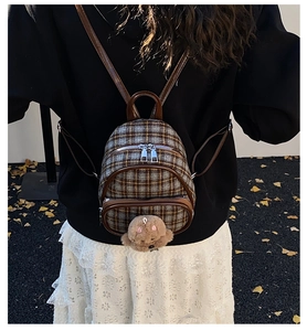 Mini plaid backpack for kids with plush bear charm worn by child in autumn setting