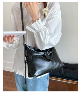 Macro detail of glossy black PU leather tote bag with elegant buckle and slim strap