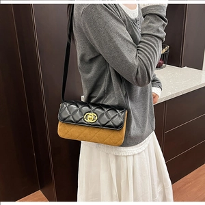Detail of two-tone quilted crossbody bag with gold metallic twist lock and black flap