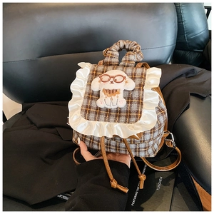 Detail of checkered mini backpack with lace trim and cartoon dog plush applique