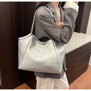 Macro detail of silver tote bag with metallic pebble leather and chain strap texture