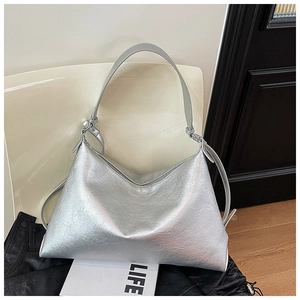 Detail showing metallic silver shoulder bag with pleated texture and adjustable strap