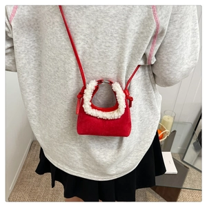 Détail d'un mini sac bandoulière rouge avec bordure en fausse fourrure blanche et nœud
