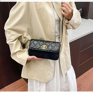 Detail of black quilted crossbody bag featuring a golden metal buckle and contrast textures