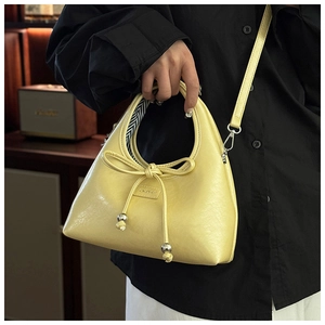 Detail of the pale yellow PU leather baguette bag with bow tie and striped lining