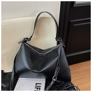 Detail of glossy pleated black leather shoulder bag with smooth metallic zipper closure