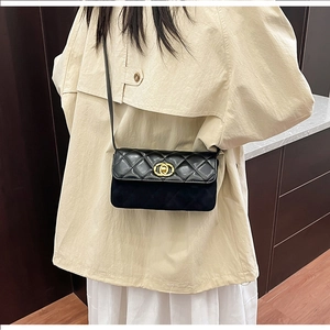 Detail of black quilted shoulder bag with gold clasp shown on a model's waist
