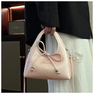 Close-up of pink crescent underarm bag with decorative bow and metallic bead details