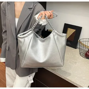 Detail of silver pleated tote bag featuring metallic chain handles and textured PU leather