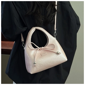 Close-up of pink crescent underarm bag with bow detail and brand logo on black shirt