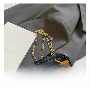 Detail of brown quilted suede bucket bag with gold chain strap and black handle