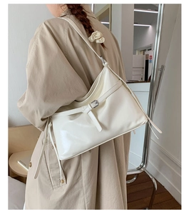 Detail of creamy white PU leather tote bag with stylish buckle and long strap detail