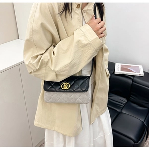 Detail of color-block quilted crossbody bag with gold lock on beige trench coat outfit