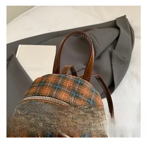 Detailed close-up of plaid tweed children backpack with brown leather handle and zipper