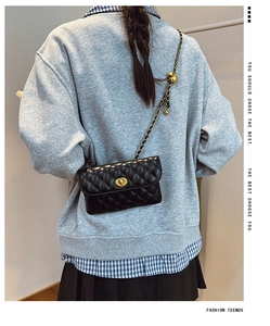 Detailansicht einer schwarzen Stepptasche mit goldener Kette auf einem Modellrücken