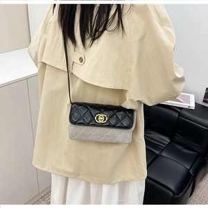 Detail of a quilted black leather and grey suede crossbody bag with gold-tone hardware