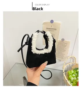 Detail of black suede mini bag with white faux fur trim and knot shoulder strap
