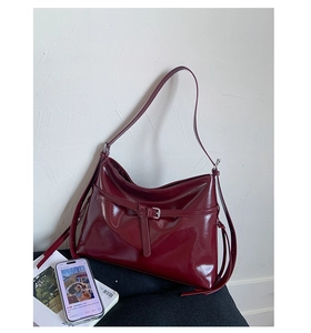 Close-up of glossy burgundy PU leather tote bag with elegant buckle and drawstring details