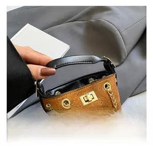 Detail of suede bucket bag with quilted base, golden chain strap and metal lock closure