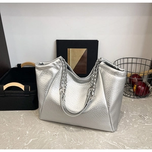 Detailed macro shot of silver tote bag with crinkled texture and sleek metal chain strap