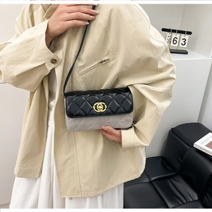 Close-up of quilted two-tone crossbody bag with interlocking gold clasp on a model