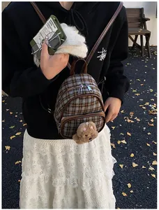 Detailed view of kids plaid mini backpack with plush bear charm and leather straps
