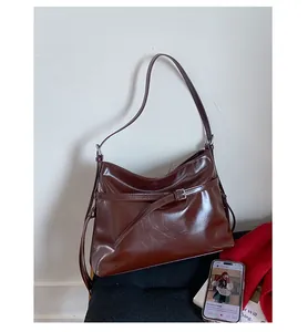 Detail of dark brown glossy PU leather shoulder bag with adjustable buckle strap detail
