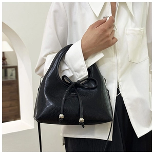 Detail of black glossy leather dumpling bag with drawstring bow and silver metal beads