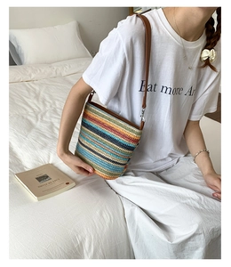 Dettaglio di una borsa a tracolla in paglia intrecciata colorata con cinturino in pelle marrone