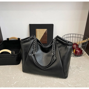 Detail of black textured PU leather tote bag with silver metal chain strap and soft finish
