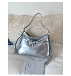 Detail of silver metallic PU tote bag with decorative buckle and stylish leather tassels