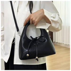 Detail of black leather crescent bag with drawstring bow and metal sphere accents