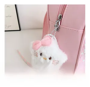 Detail of cute cat plush pendant with pink bow on sequined girl backpack zipper
