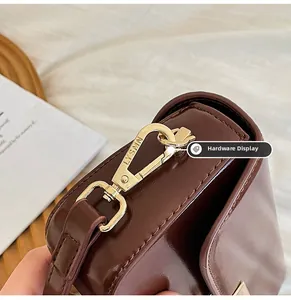 Close-up of the elegant gold metal lock with LYSMN engraving on a brown leather bag